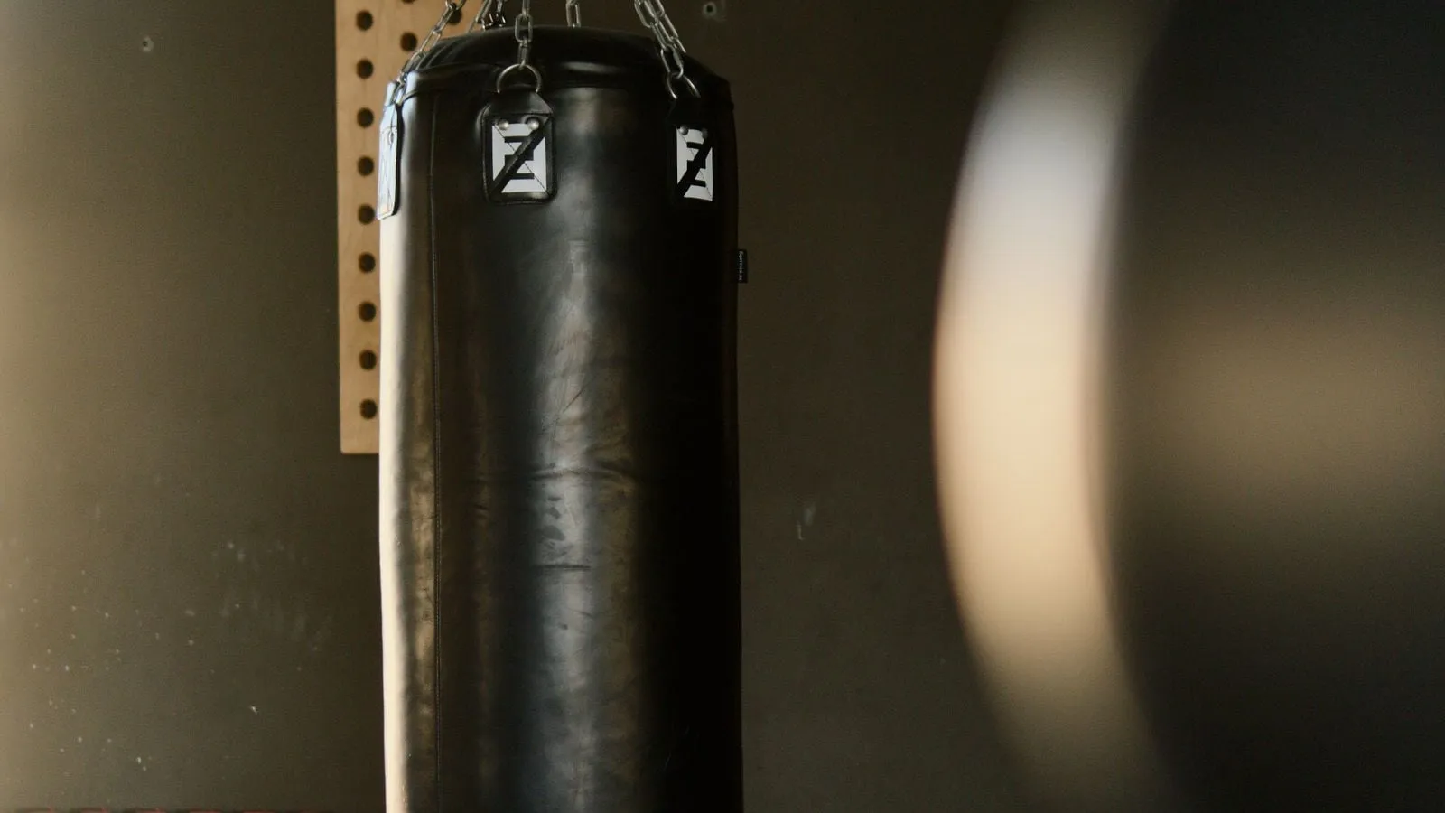 Heavy punching bag hanging in a dark gym