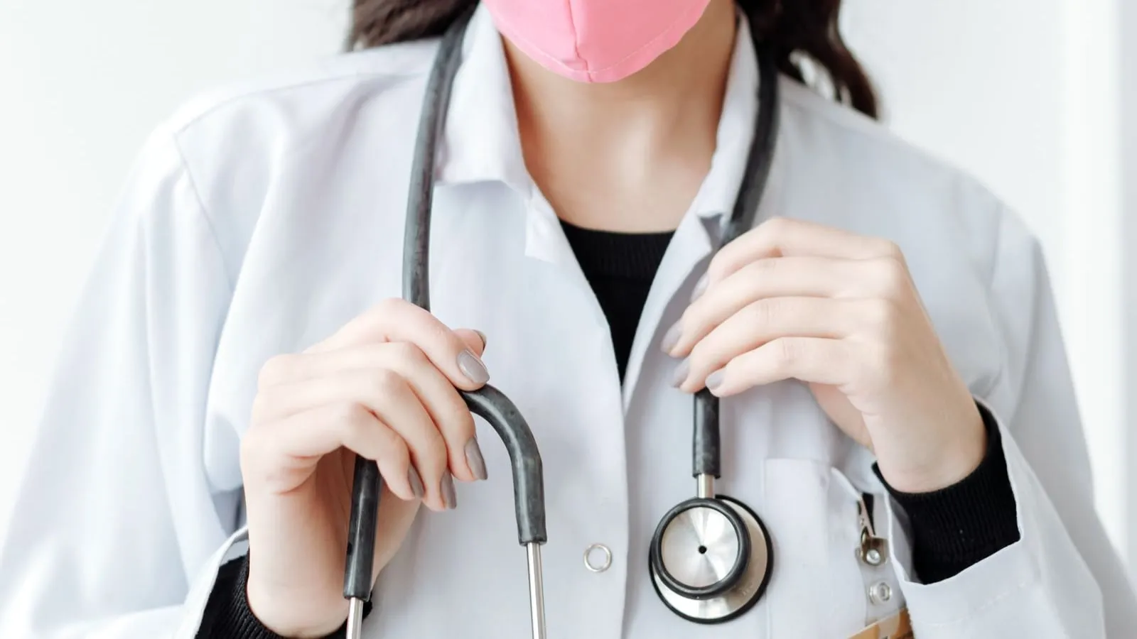 Clinician in a white coat holding a stethoscope