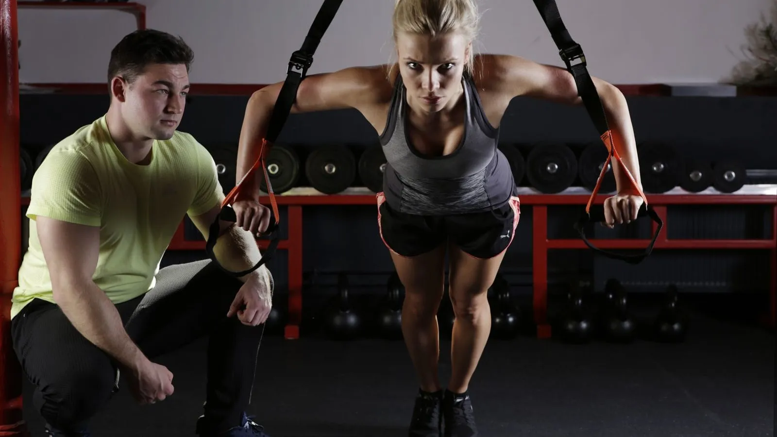 Woman training on suspension straps while a coach looks on